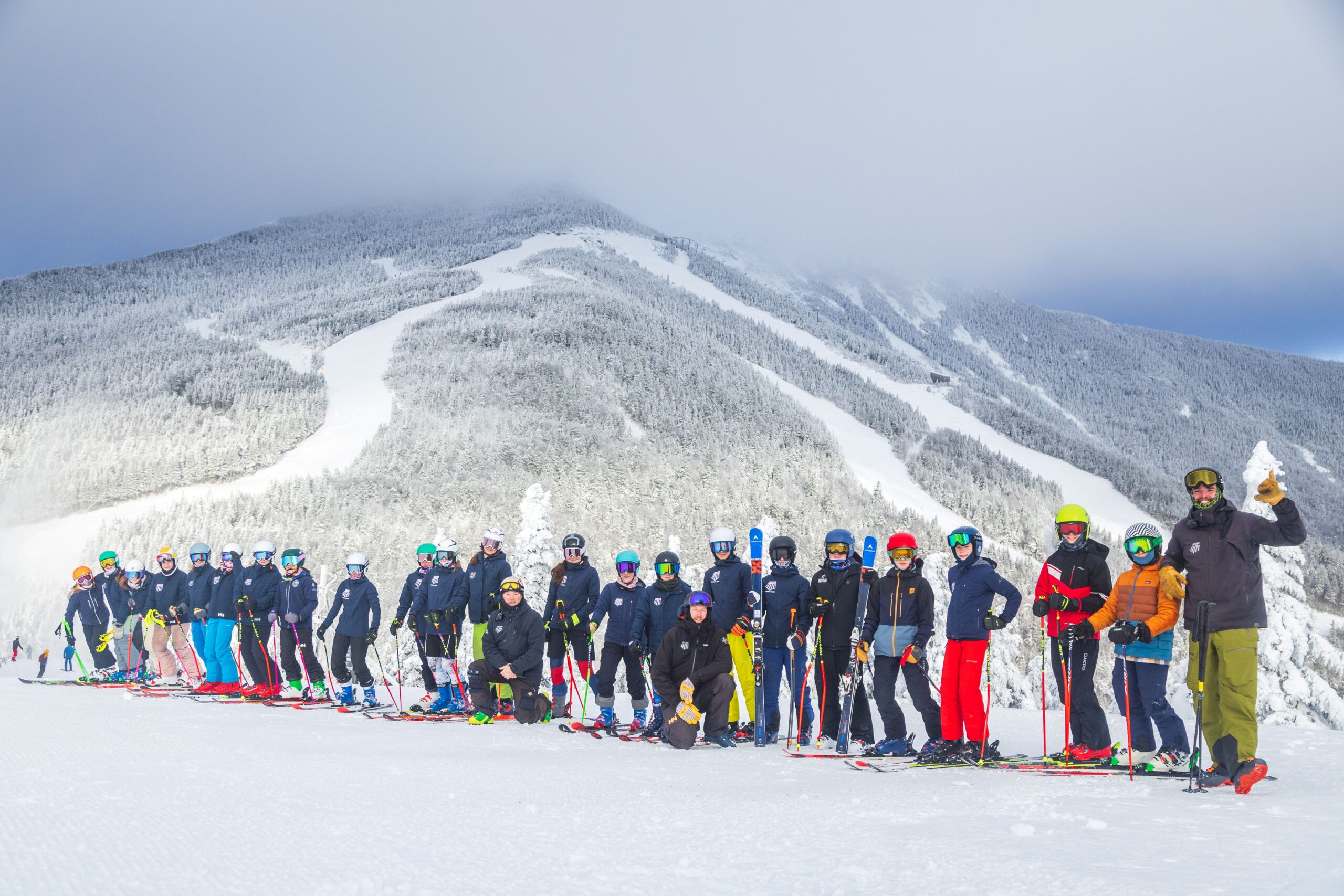 line of kids in ski gear with whiteface mountain in the background